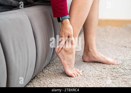 Douleur au pied, femme asiatique assise sentant douleur au pied à la maison, femme souffrant de douleur au pied utilisant le massage de la main pour détendre les muscles de la plante des pieds Banque D'Images