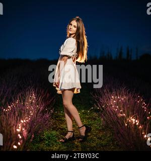 Ivano-Frankivsk, Ukraine 28 juillet 2023 : la fille est entre les rangées de lavande, les buissons de lavande et les fleurs sont illuminés par des guirlandes, aromathérapie Banque D'Images