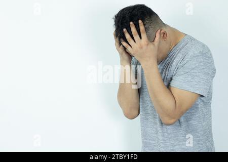 Portrait de l'homme asiatique déprimé cachant son visage avec les mains. Stressé, désespéré, frustré, trouble mental, cœur brisé et problèmes psychologiques. Banque D'Images