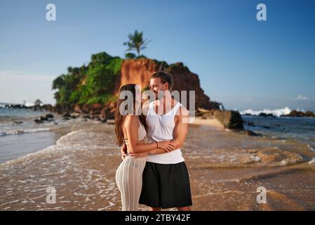 Couple romantique embrasse sur la plage de sable au coucher du soleil. L'homme et la femme apprécient la mer tropicale, l'amour et le concept de voyage. Happy pair partage affectueux Banque D'Images