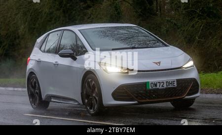 Milton Keynes,Bucks,UK - Dec 9th 2023 : 2022 blanc Cupra née V1 voiture électrique conduisant sur une route mouillée, sous la pluie avec les phares allumés Banque D'Images