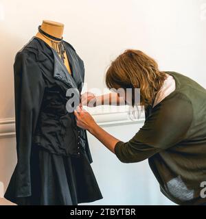 Créateur de mode habillant un mannequin avec des vêtements noirs Banque D'Images