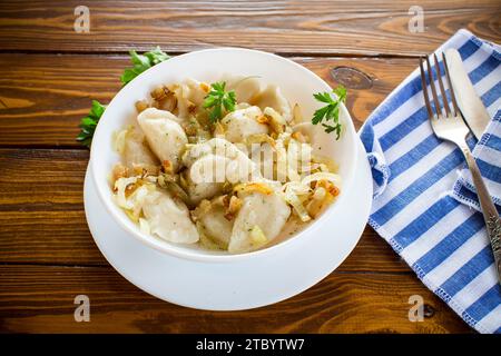 Boulettes ukrainiennes farcies de pommes de terre et de champignons, servies avec des oignons frits. Fond de table en bois. Photo de haute qualité Banque D'Images