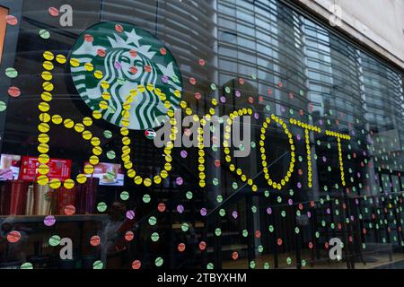 Londres, Royaume-Uni. 9 décembre 2023. Des autocollants indiquant « boycott » ont été plâtrés sur les fenêtres d'une succursale de Starbucks à Londres. Banque D'Images