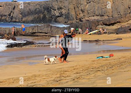 Femme aidant un surfeur blessé, avec chien de compagnie concerné, El Cotillo, Fuerteventura, Îles Canaries, Espagne. Prise en novembre 2023 Banque D'Images