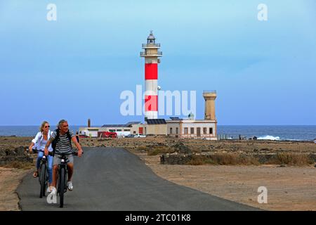 Couple mature à vélo au phare de Faro del Tóston et musée de la pêche, El Cotillo, Fuerteventura, Îles Canaries, Espagne. Prise en novembre 2023 Banque D'Images