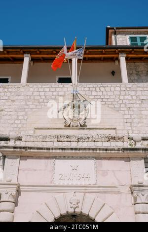 Les drapeaux flottent sur un mât au-dessus des armoiries sur l'ancienne porte de la mer. Kotor, Monténégro Banque D'Images