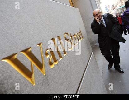 New York, États-Unis - 07 NOVEMBRE 2011. Un homme passe par Wall Street signe-marque-étiquette de la célèbre rue financière de New York, Wall Street. Banque D'Images