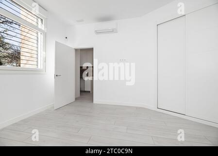 Une pièce vide avec une baie vitrée dans une maison de style loft avec une armoire intégrée à deux sections avec des portes coulissantes en bois blanc Banque D'Images