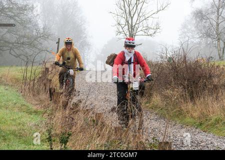 9 décembre 2023. Les concurrents qui font du vélo tout-terrain dans le Dirty Santa MTB Trail cyclable dans les Surrey Hills, en Angleterre, au Royaume-Uni. Beaucoup de cyclistes portaient des costumes de fantaisie sur le thème de Noël, et devenaient très boueux sur la route hors route à travers la région de Surrey Hills de beauté naturelle exceptionnelle. Banque D'Images