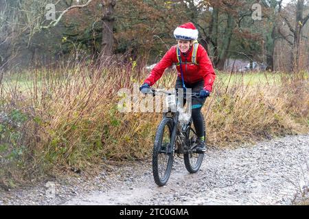 9 décembre 2023. Les concurrents qui font du vélo tout-terrain dans le Dirty Santa MTB Trail cyclable dans les Surrey Hills, en Angleterre, au Royaume-Uni. Beaucoup de cyclistes portaient des costumes de fantaisie sur le thème de Noël, et devenaient très boueux sur la route hors route à travers la région de Surrey Hills de beauté naturelle exceptionnelle. Banque D'Images