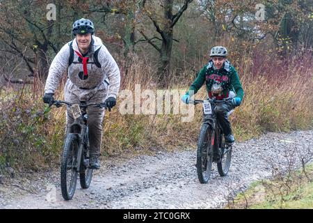 9 décembre 2023. Les concurrents qui font du vélo tout-terrain dans le Dirty Santa MTB Trail cyclable dans les Surrey Hills, en Angleterre, au Royaume-Uni. Beaucoup de cyclistes portaient des costumes de fantaisie sur le thème de Noël, et devenaient très boueux sur la route hors route à travers la région de Surrey Hills de beauté naturelle exceptionnelle. Banque D'Images