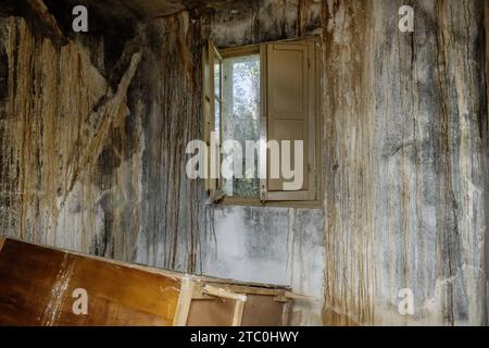 Fenêtre en bois d'un ancien bâtiment abandonné avec de grandes taches sur les murs Banque D'Images