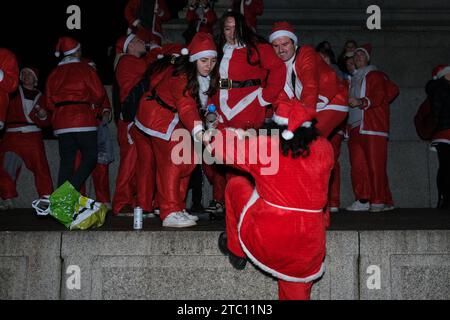 Londres, Royaume-Uni. 9 décembre 2023. Les fêtards de SantaCon vêtus de costumes du Père Noël et d'autres costumes festifs arrivent à Trafalgar Square où ils ont posé pour des photos de groupe au pied de la colonne Nelson. L’événement annuel, qui voit les participants prendre part à un pub crawl, est également organisé dans d’autres villes du monde. Crédit : Photographie de onzième heure / Alamy Live News Banque D'Images