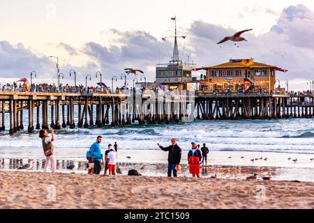 Touristes prenant des photos sur Santa Monica Beach, avec Santa Monica Pier en arrière-plan, après-midi d'été dans le sud de la Californie Banque D'Images