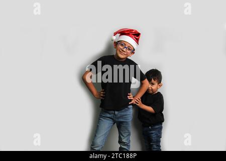 Enfants latinos à la peau foncée, frère aîné dans le chapeau de Santa prend soin de son jeune frère et passe du temps de qualité aux vacances pour célébrer Banque D'Images