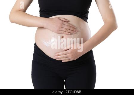 Une femme enceinte applique de la crème vergetures sur son ventre Banque D'Images