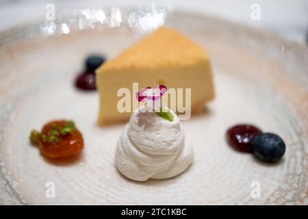 Une tranche de cheesecake servi sur assiette avec sauce aux baies et crème fouettée Banque D'Images