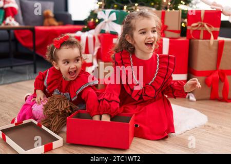 Adorables filles célébrant noël déballage poupée de cadeau à la maison Banque D'Images