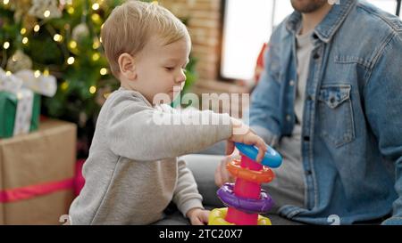 Père et fils célébrant noël en jouant avec des jouets à la maison Banque D'Images