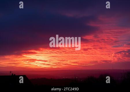 West Yorkshire, Royaume-Uni. 10 décembre 2023. UK Météo. Northowram, West Yorkshire, Royaume-Uni. Un magnifique lever de soleil après la tempête Elin sur les Pennines vu du village de Northowram près de Halifax, West Yorkshire avec l'émetteur classé Grade 2 de Emley Moor sur la ligne d'horizon. Crédit : Windmill Images/Alamy Live News Banque D'Images