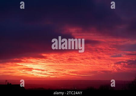 West Yorkshire, Royaume-Uni. 10 décembre 2023. UK Météo. Northowram, West Yorkshire, Royaume-Uni. Un magnifique lever de soleil après la tempête Elin sur les Pennines vu du village de Northowram près de Halifax, West Yorkshire avec l'émetteur classé Grade 2 de Emley Moor sur la ligne d'horizon. Crédit : Windmill Images/Alamy Live News Banque D'Images