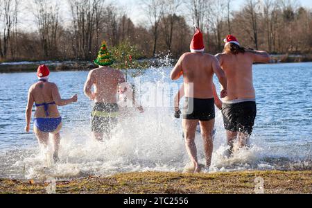 Ertingen, Allemagne. 10 décembre 2023. Des hommes et une femme en chapeaux de Père Noël sautent dans le Schwarzachtalsse pour un plongeon dans les températures à un chiffre le 2e Avent. Crédit : Thomas Warnack/dpa/Alamy Live News Banque D'Images