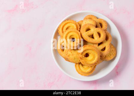 Ensemble de biscuits au beurre danois macro découpe. Cinq bretzel entier, biscuits sablés ronds et rectangulaires avec du sucre sur fond rose. Pâtisserie danoise Banque D'Images