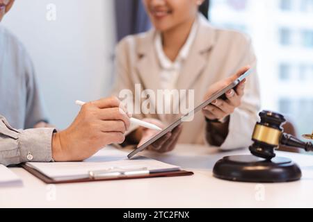 Homme d'affaires senior signant le contrat sur tablette tandis que l'avocate femme explique la durée et l'accord juridique. Banque D'Images