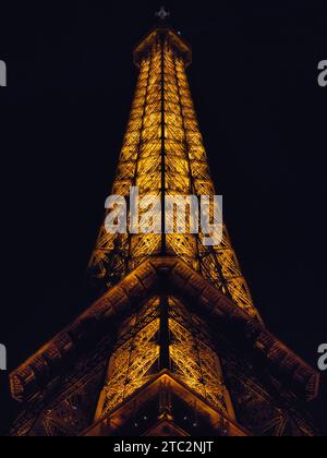 Tour Eiffel à Paris, France, illuminée la nuit et vue d'en bas, une vue verticale spectaculaire du monument emblématique contre un ciel sombre Banque D'Images