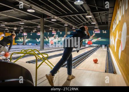 Un adolescent fait descendre une boule de bowling dans une piste de bowling de 10 quilles Banque D'Images