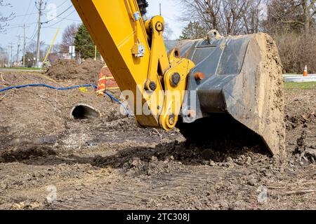 Godet ou pelle d'excavatrice sur le chantier de construction de routes. Entretien, entretien et réparation des infrastructures et des équipements de terrassement Banque D'Images