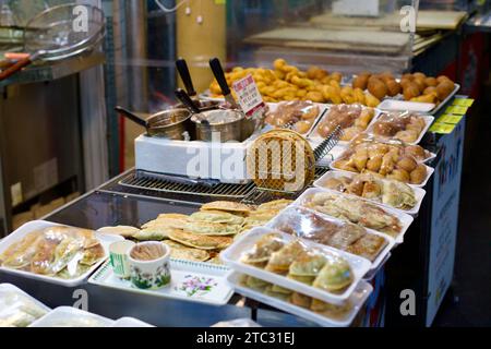 Une délicieuse sélection d'en-cas rapides, y compris des gaufres croustillantes et du mandu savoureux, offre un avant-goût de la cuisine de rue locale sur un marché coréen traditionnel. Banque D'Images