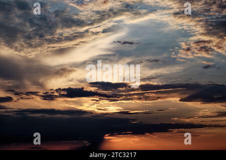 Le soleil brille à travers les nuages éparpillés au coucher du soleil. Banque D'Images