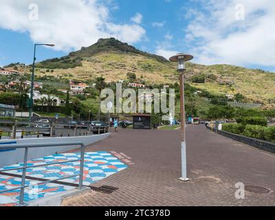 Machico, Madère, Portugal, 17 mai 2022 : rue piétonne, promenade au bord de la mer et bâtiments à Machico. Colline verte en arrière-plan Banque D'Images