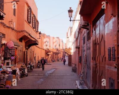 Vendeurs de rue et bâtiments en argile rouge dans la médina de Marrakech aka Marrakech avec Mosquée au loin, Maroc, 10 décembre 2023 Banque D'Images