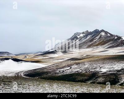 Route sinueuse à travers les hautes terres enneigées d'Islande Banque D'Images