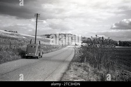 Années 1950, historique, une voiture de l'époque garée sur une route de campagne dans les collines de Shropshire, Shropshire, Angleterre, Royaume-Uni. Bordant le pays de Galles, dans une zone connue sous le nom de Marche galloise, le terrain montagneux des collines est répertorié comme un AONB, une zone de beauté naturelle exceptionnelle. Banque D'Images