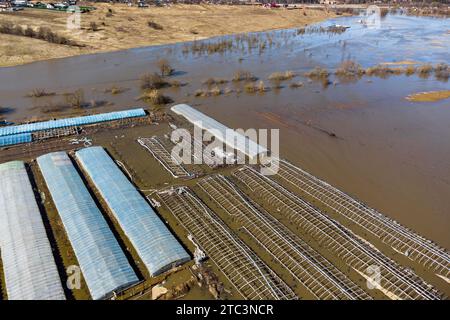 Vue aérienne des serres de ferme inondées pendant l'inondation printanière, crue de rivière grave Banque D'Images