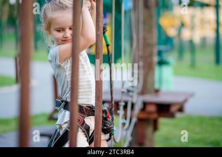 Jolie fille profitant de l'activité dans un parc d'aventure d'escalade. Fille va sur la piste articulée. Banque D'Images