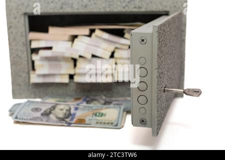 Petit coffre-fort à la maison plein de paquets d'argent dans différentes devises, isolé sur un fond blanc Banque D'Images