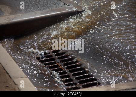 Écoulement de l'eau pendant les fortes pluies et colmatage des eaux usées de la rue. L'écoulement de l'eau lors d'un fort ouragan dans les égouts pluviaux. Système de tempête d'eaux usées le long Banque D'Images