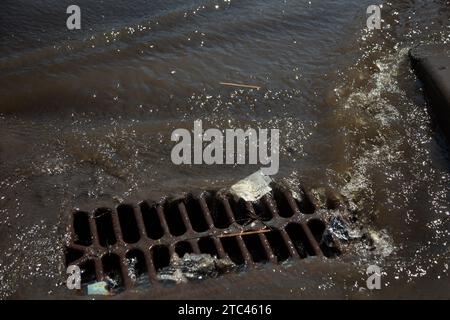 Écoulement de l'eau pendant les fortes pluies et colmatage des eaux usées de la rue. L'écoulement de l'eau lors d'un fort ouragan dans les égouts pluviaux. Système de tempête d'eaux usées le long Banque D'Images