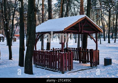 vieux belvédère en bois dans un parc d'hiver par une journée ensoleillée. belvédère en bois dans le parc. belvédère en bois recouvert de neige dans le parc. Banque D'Images