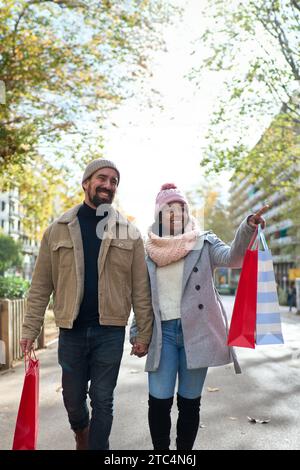 Beau jeune couple interracial dans l'amour profitant de la saison des vacances d'hiver dans les rues de la ville Banque D'Images