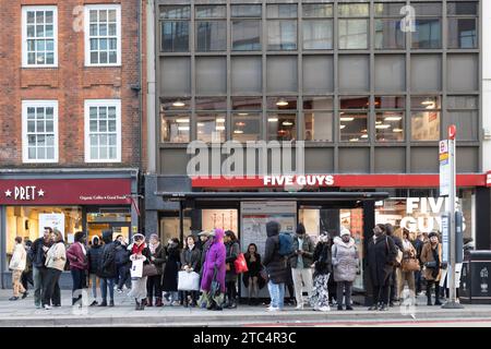 LONDRES, ANGLETERRE - 12 décembre 2023 personnes attendent le bus à l'arrêt. Des représentants de différentes nationalités vivent à Londres. East Lo Banque D'Images