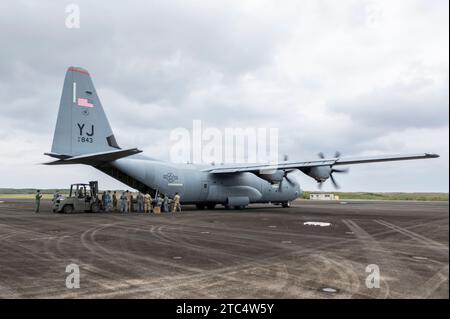 Une équipe de forces d'autodéfense maritime américaines, japonaises, et les aviateurs de la Royal Australian Air Force pratiquent une technique de déchargement de combat avec un C-130J Super Hercules du 36th Airlift Squadron, lors de l'exercice Cope North 23, à la base aérienne Iwo to Japan Maritime Self Defense Force, Japon, le 21 février 2023. Les déchargements de combat sont des méthodes manuelles de largage de fret par transport aérien pour déplacer en toute sécurité les palettes de fret sans l'aide d'équipement lourd, ce qui est utile pour livrer la cargaison sur les pistes d'atterrissage temporaires ou pour décharger rapidement dans les zones contestées. COPE North 23 est une assistance humanitaire multilatérale Banque D'Images