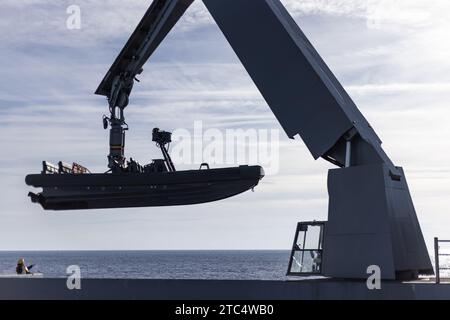 Un marin de l'US Navy avec l'USS New York (LPD 21) utilise une grue pour décharger un bateau gonflable à coque rigide pendant l'Amphibious Squadron, Marine Expeditionary Unit (MEU) Integration (PMINT) dans l'océan Atlantique, le 8 décembre 2023. PMINT est la première occasion pour le 24e MEU dans le cycle de formation pré-déploiement de s’intégrer pleinement au Wasp Amphibious Ready Group. Pendant le PMINT, les Marines et les marins sont testés dans toutes les capacités opérationnelles requises et dans l'environnement d'entraînement projeté à travers une variété d'événements simulés et en direct. (Photo du U.S. Marine corps par lance Cpl Ryan Ramsammy) Banque D'Images