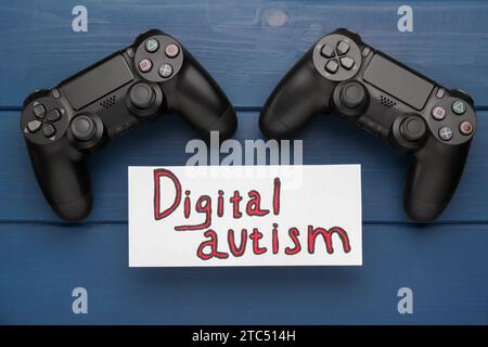 Carte avec phrase Digital Autism sur table en bois bleu, plat. Comportement addictif Banque D'Images