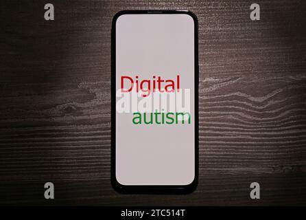 Smartphone avec phrase Digital Autism sur table en bois, vue de dessus. Comportement addictif Banque D'Images